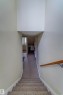 Carpeted staircase with a wood handrail leading to a carpeted hallway