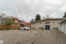 Rear exterior featuring a blue entrance door, multiple windows, and an asphalt parking area