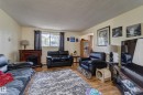 Spacious living area featuring wood-finish flooring, a decorative fireplace, and ample natural light from a window with dark curtains