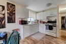 Kitchen featuring white cabinetry, gray countertops, wood-finish flooring, a window with horizontal blinds, and a built-in oven with overhead ventilation