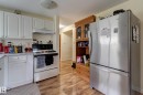 Kitchen featuring white cabinetry, white countertops, built-in range with overhead exhaust, and wood-finish flooring