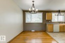 Dining area featuring wood-finish flooring, two large windows with blinds, and an overhead chandelier