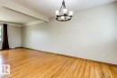Expansive room featuring wood-finish flooring, a contemporary chandelier light fixture, neutral wall colors, and a large window