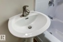 White pedestal sink with a brushed nickel single-handle faucet