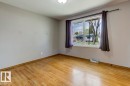 Room featuring wood-finish flooring, a window with white trim, and a ceiling-mounted light fixture