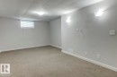 Spacious room with light gray walls, neutral carpet flooring, and a drop ceiling