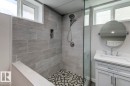 Shower with large format gray wall tile, built-in niche, and mosaic tile flooring