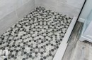 Walk-in shower featuring gray subway tile walls and a hexagonal mosaic tile floor with a central drain