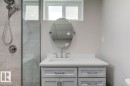 Bathroom featuring a light gray vanity with chrome hardware, an oval mirror, and a white countertop