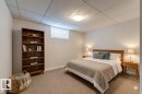 Carpeted room featuring a wood-finish bookcase, white walls, and a drop ceiling with a flush-mount light fixture