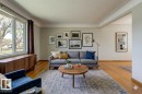Living area featuring wood-finish flooring, a broad picture window, a built-in wood-finish console, and crown molding