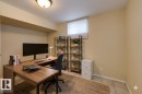 Dedicated workspace featuring a wood-finish L-shaped desk, recessed lighting, and tile flooring