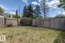 Fenced backyard featuring natural grass, perimeter garden beds, and mature shrubs