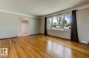 Spacious living area featuring polished wood flooring, a large multi-pane window, neutral wall tones, and crown molding
