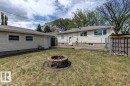 Backyard featuring a stone fire pit, concrete patio, and a detached garage with siding