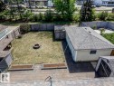 Expansive backyard featuring a central fire pit, natural grass lawn, and a wooden privacy fence