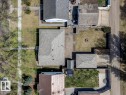 Overhead property view featuring a shingled roof, a detached garage, a fire pit area, and a concrete driveway