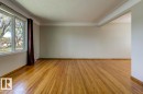 Spacious interior room featuring wood flooring, a multi-pane window, neutral wall paint, and white crown molding