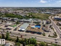 Aerial perspective of a commercial district featuring multiple business properties, extensive surface parking, and direct access to a multi-lane roadway
