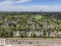 Expansive aerial perspective showcasing a residential area with varied housing styles, mature trees, and a distant city skyline