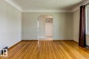 Spacious room featuring wood-finish flooring, light-toned walls, and crown molding