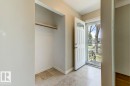 Foyer featuring neutral wall paint, tiled flooring, a built-in coat closet with a hanging rod, a paneled entry door with an arched glass insert, and a screen door