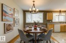 Open-concept dining area featuring a wood-finish flooring, a round dining table, and an overhead chandelier with frosted glass shades