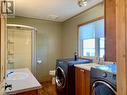 Oversized main bathroom has a shower and laundry area with high quality front-loading washer/dryer, laundry basin, and built-in storage cabinetry above & below.