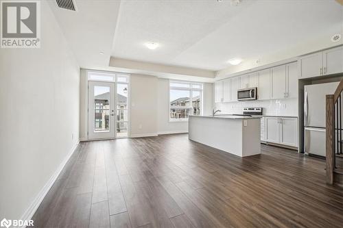 Kitchen with appliances with stainless steel finishes, backsplash, a kitchen island with sink, sink, and dark hardwood / wood-style floors