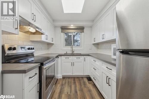 Kitchen featuring white cabinets, sink, appliances with stainless steel finishes, and dark wood-type flooring