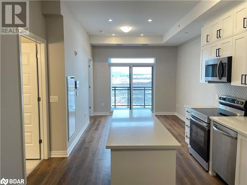 Kitchen featuring decorative backsplash, appliances with stainless steel finishes, dark wood-type flooring, white cabinets, and a kitchen island