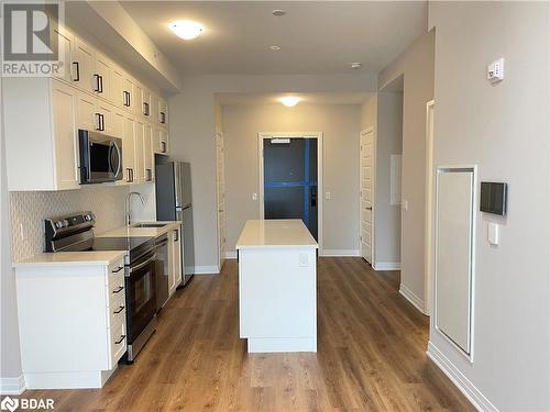 Kitchen featuring appliances with stainless steel finishes, backsplash, sink, hardwood / wood-style floors, and white cabinetry