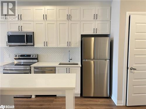 Kitchen featuring sink, stainless steel appliances, dark hardwood / wood-style floors, backsplash, and white cabinets