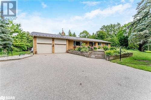 Ranch-style house featuring a garage, driveway, brick siding, a chimney, and a front yard