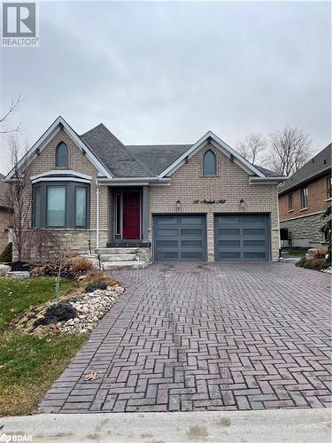 View of front of house with brick siding, decorative driveway, and an attached garage