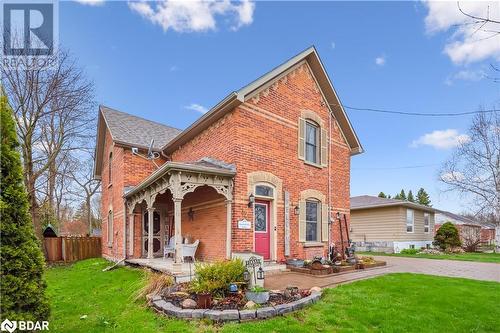 Back of house featuring fence, brick siding, a shingled roof, a porch, and a yard