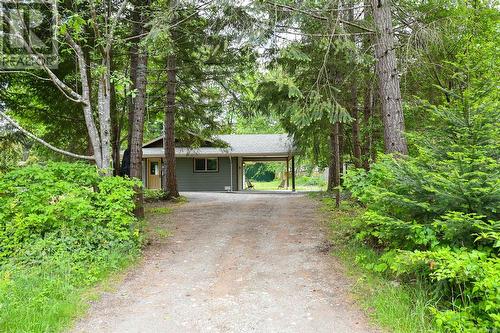 View of front of house with driveway, an attached carport, and roof with shingles