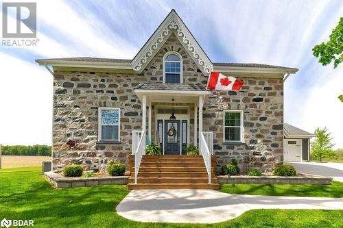 View of front of property featuring stone siding, a front yard, and driveway