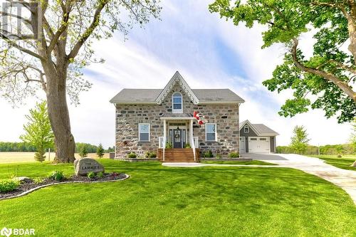 View of front of house with concrete driveway, stone siding, a front yard, and a garage