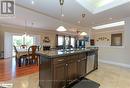 Kitchen featuring ornamental molding, a center island with sink, light wood-type flooring, dark brown cabinetry, and dishwasher