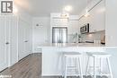 Kitchen featuring white cabinets, stainless steel appliances, a peninsula, and a kitchen bar
