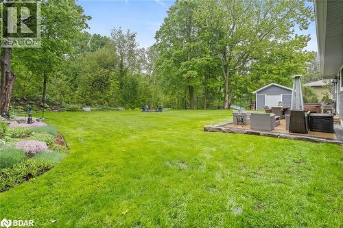 View of grassy yard featuring a patio area, view of wooded area, an outdoor structure, and an outdoor living space
