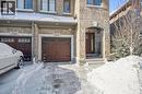 Snow covered property entrance with stone siding and a garage