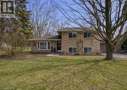 Split level home featuring stucco siding, a front yard, and brick siding