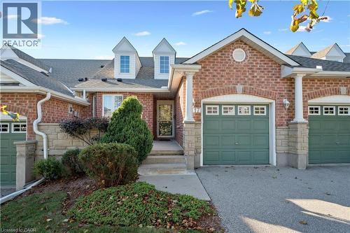 View of front of home featuring a shingled roof, an attached garage, brick siding, stone siding, and driveway