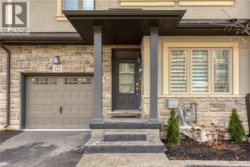 Property entrance with stone siding, an attached garage, driveway, and stucco siding