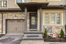 Property entrance with stone siding, an attached garage, driveway, and stucco siding