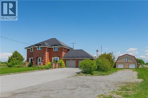 View of front of house featuring brick siding, an outbuilding, driveway, and a detached garage