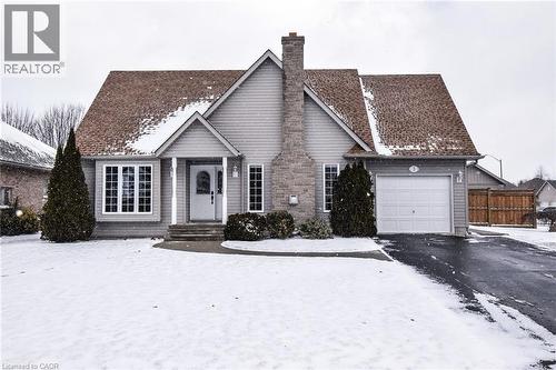 View of front of home featuring a chimney, asphalt driveway, and a garage