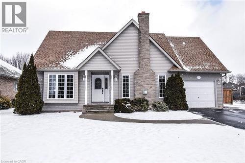 View of front of house with driveway, a chimney, and a garage
